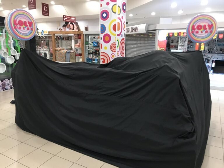 Proteção noturna com capa preta sob medida para quiosque de doces e guloseimas localizado no meio do corredor do shopping.