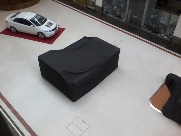 Capa preta protetora feita sob medida para quiosque retangular, instalada no corredor principal do shopping. Fechamento rápido e padrão visual exigido pela administração.